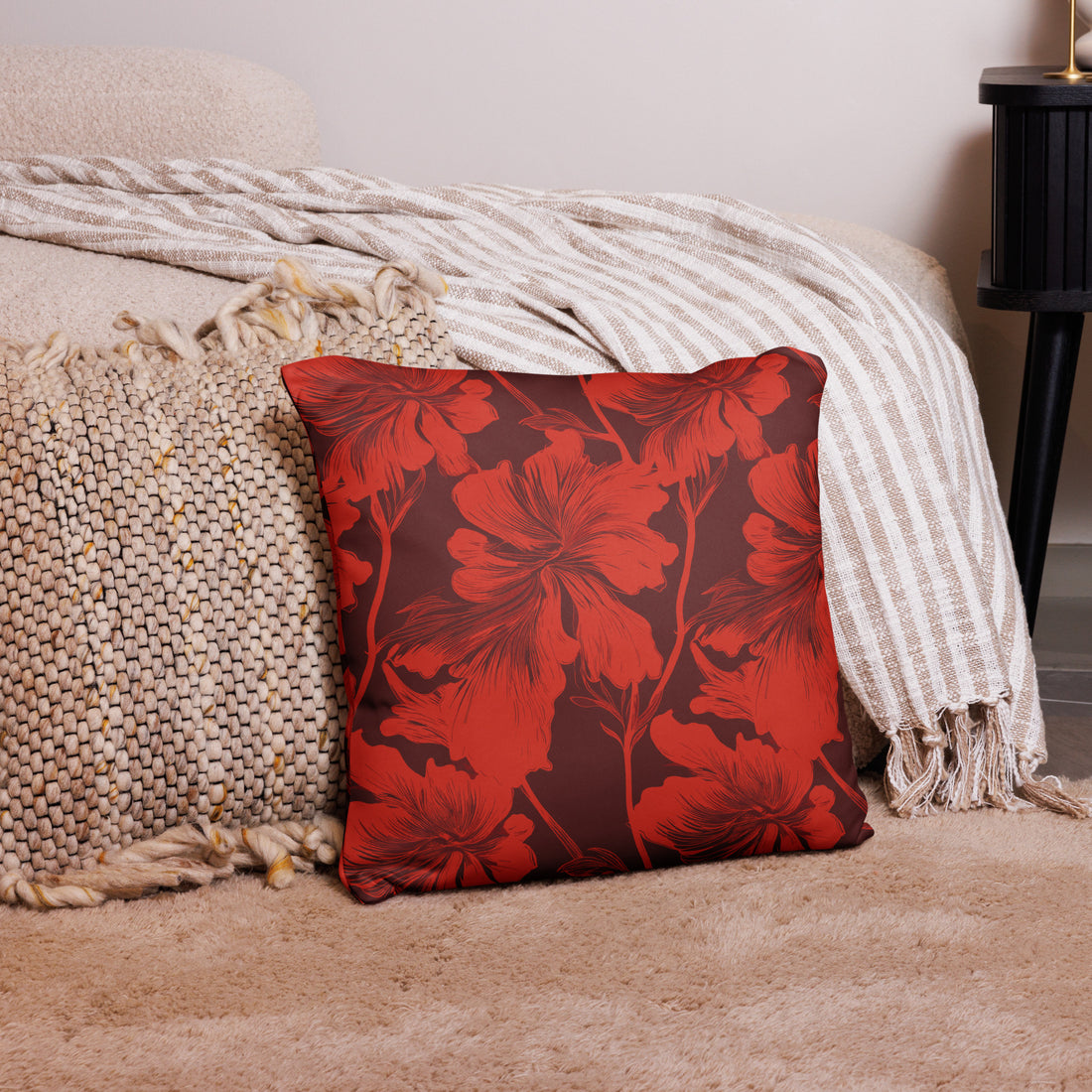 Red Hibiscus Floral Decorative Knitted Pillow on a cozy beige rug and next to patterned textiles.