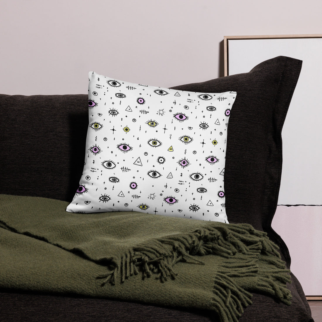 Mystical Eye Pattern Pillow in black, white, and pastel hues, on a sofa with a blanket