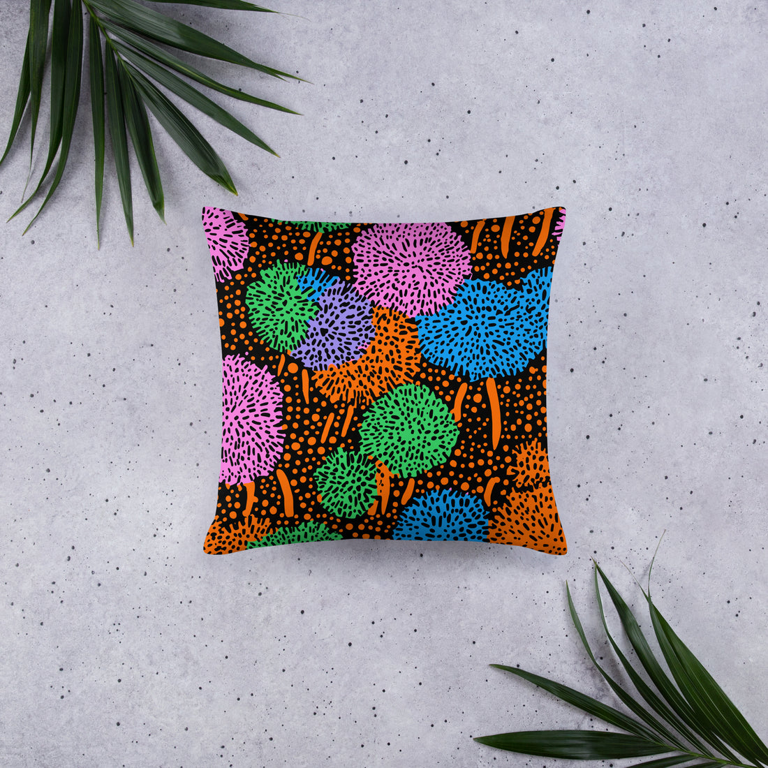 Vibrant geometric print throw pillow featuring multicolored pom-pom designs on a black background.