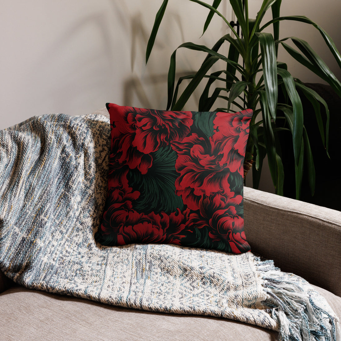 Vibrant floral accent pillow with red flowers on a dark green background, placed on a cozy sofa.