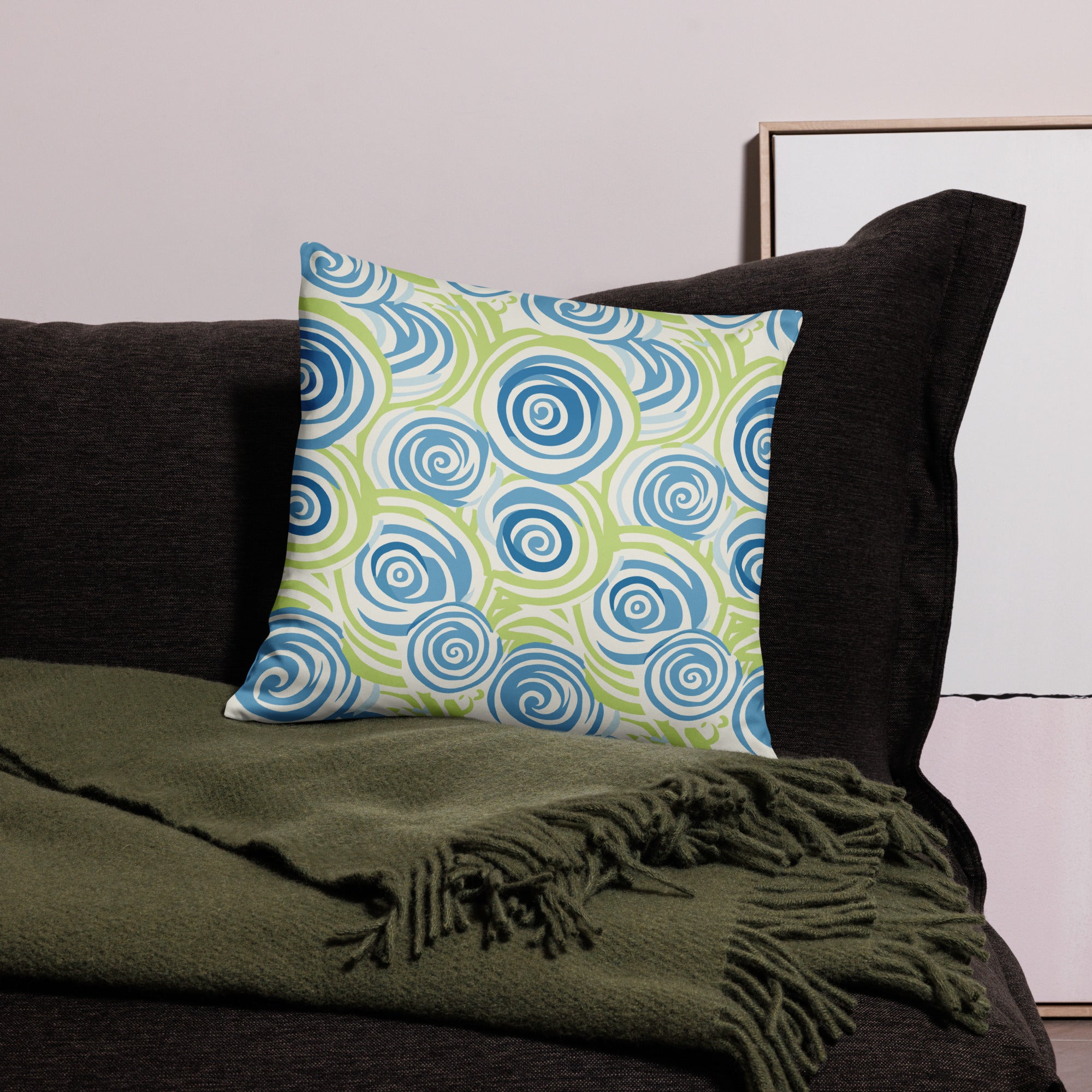 A knitted pillow with swirling blue and green spiral patterns, perfect for winter decor.