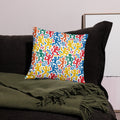 Colorful pillow featuring lively abstract dance figures in red, blue, green, yellow, and orange tones on a cozy sofa setting.