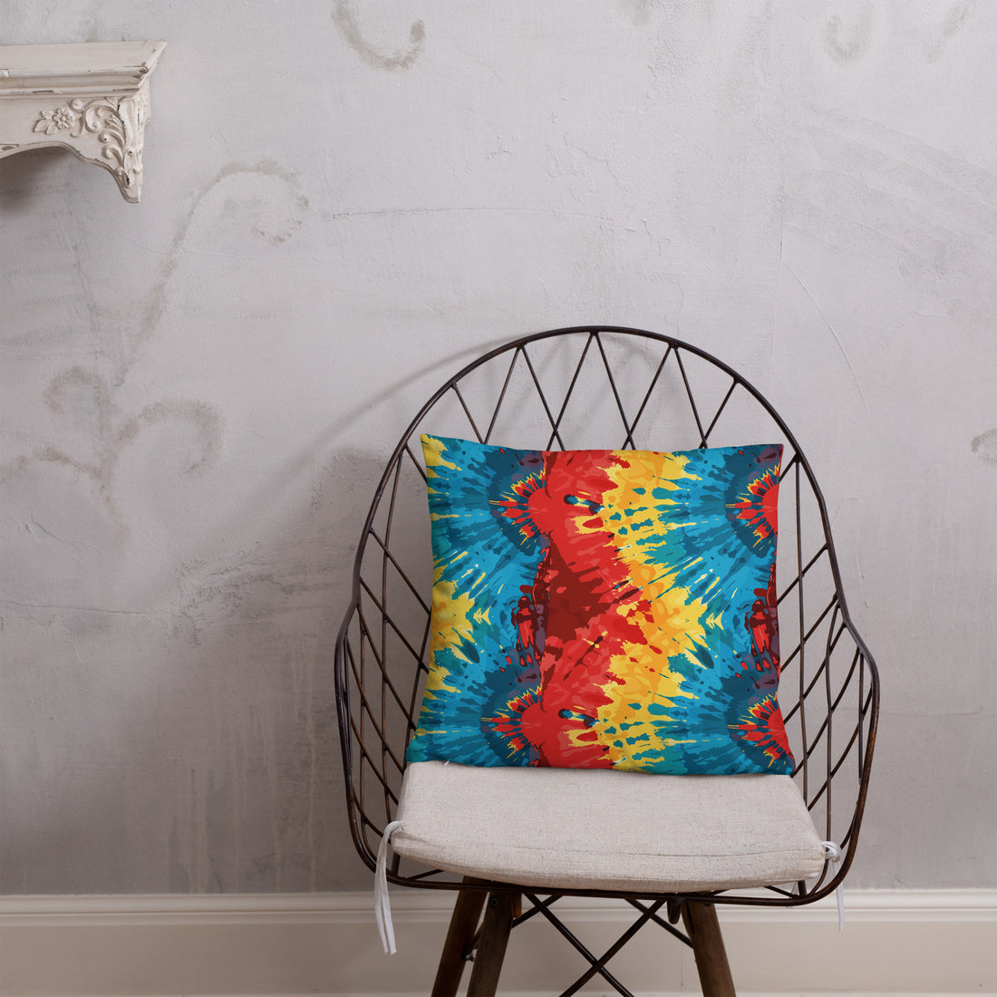 Bright parrot kaleidoscope pillow with bold red, blue, and yellow patterns against a textured wall.