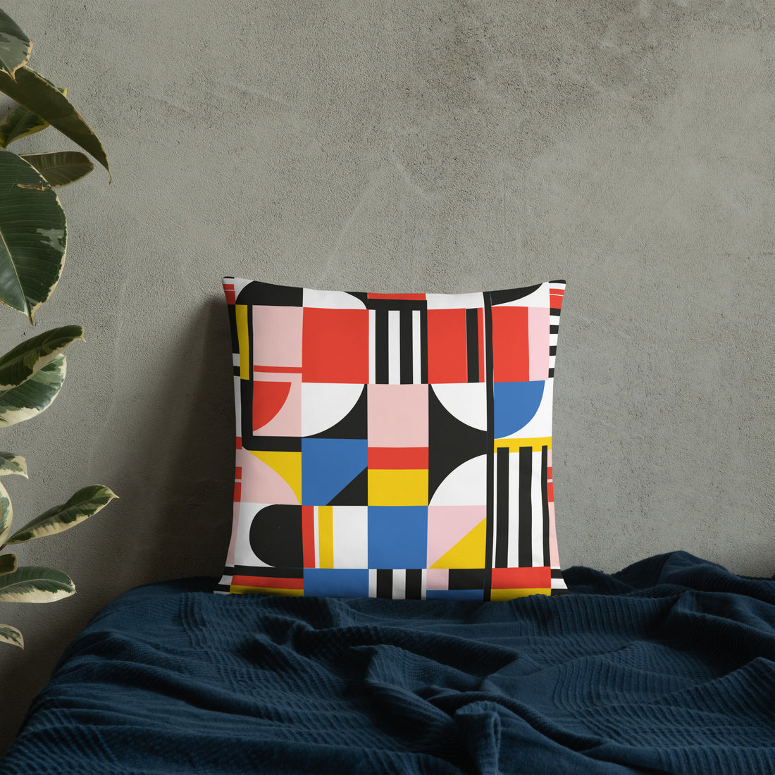 Vibrant geometric accent pillow with red, blue, yellow, and black patterns on a textured grey background.