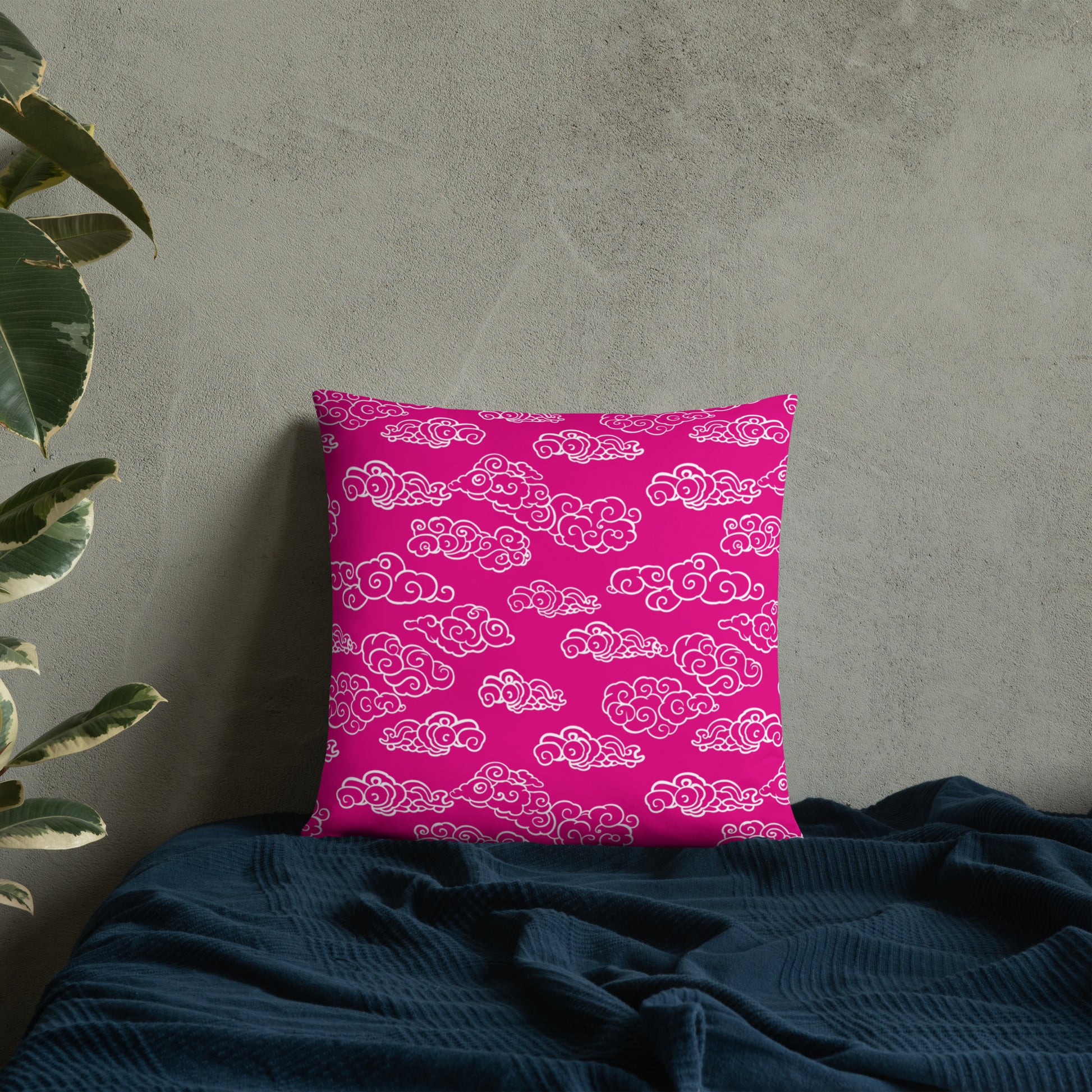 Festive Pink Cloud Knitted Accent Pillow on a dark bedspread with a gray wall background