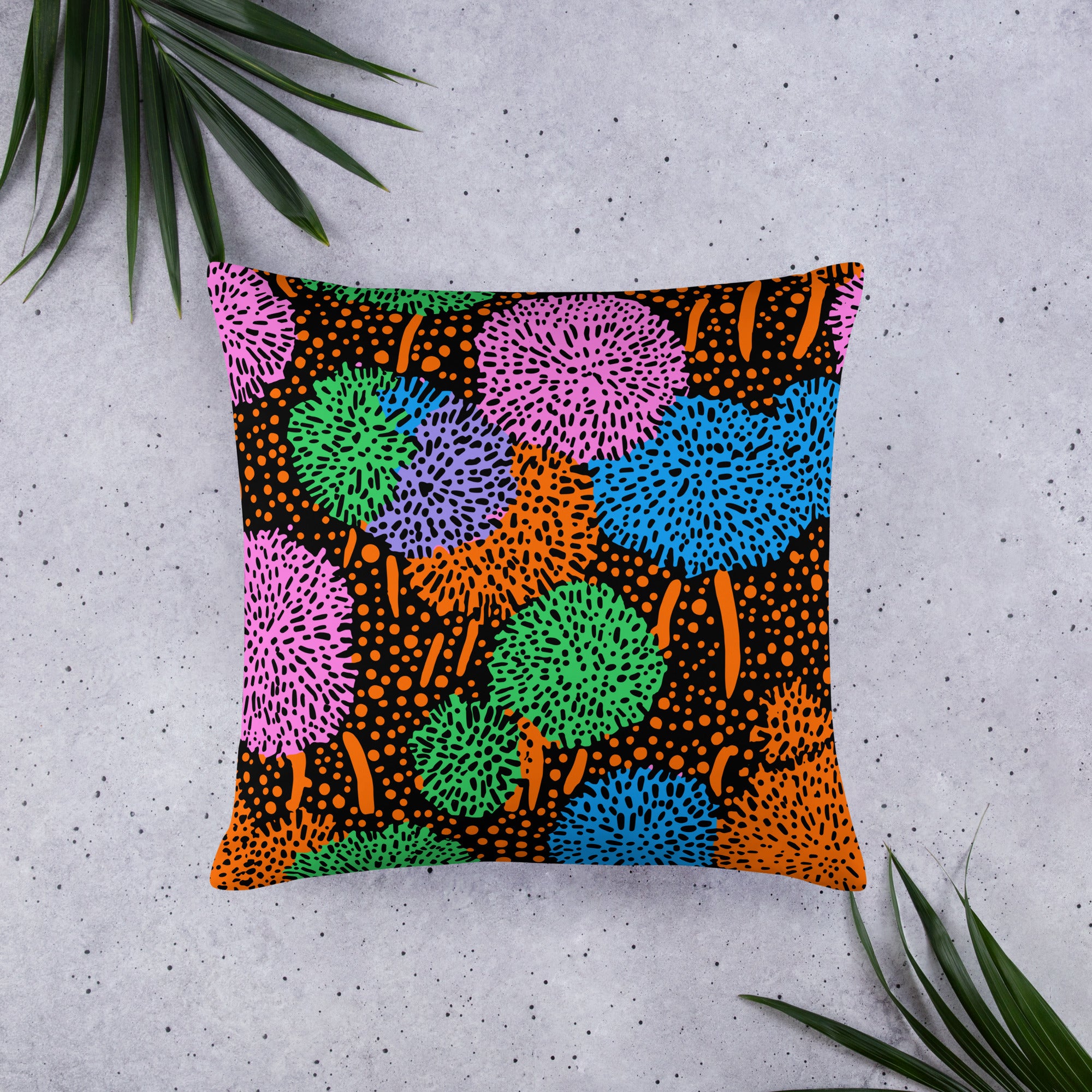 Vibrant geometric print throw pillow featuring multicolored pom-pom designs on a black background.