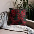 Vibrant floral accent pillow with red flowers on a dark green background, placed on a cozy sofa.