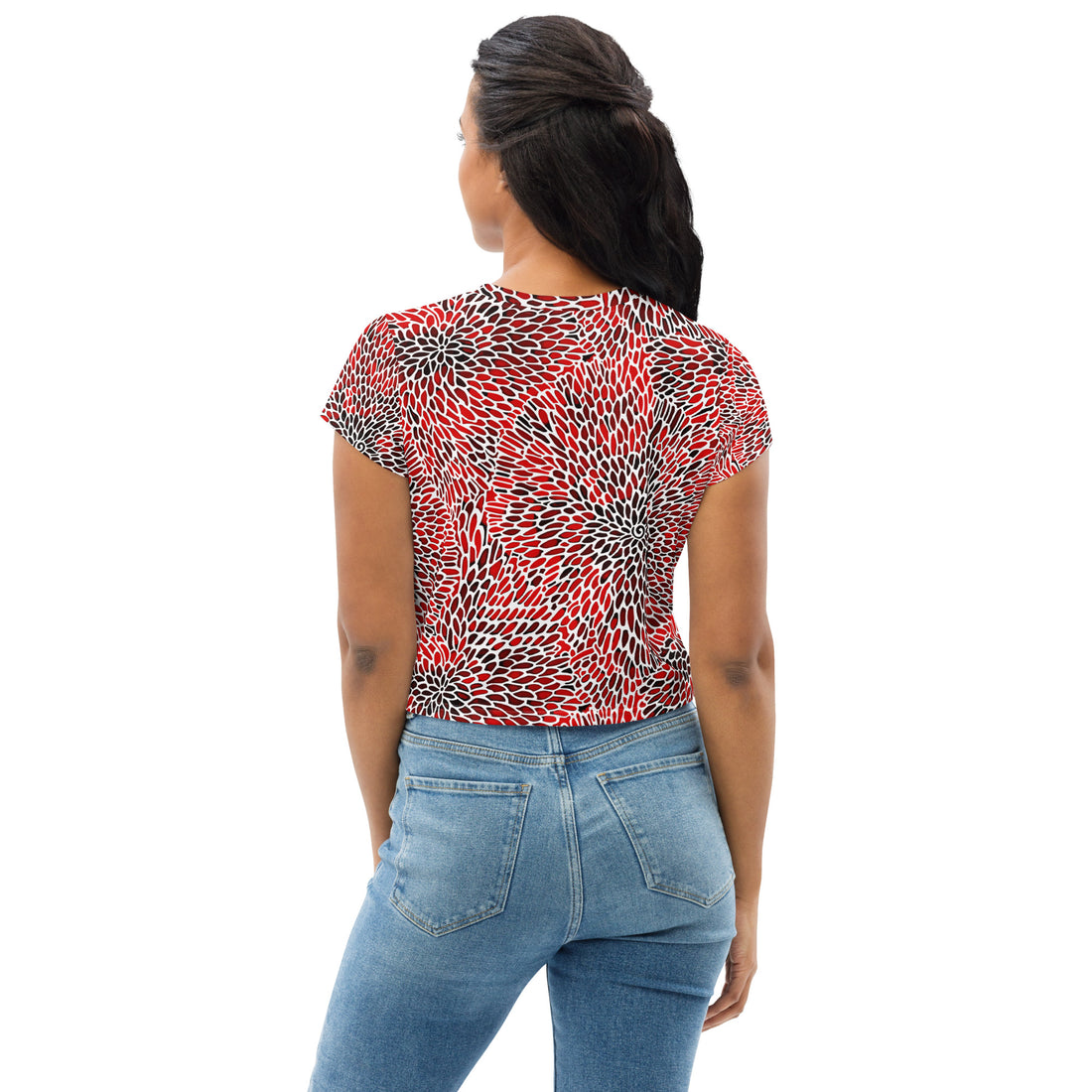 Vibrant abstract print crop tee in red, black, and white worn by a woman standing with blue jeans.