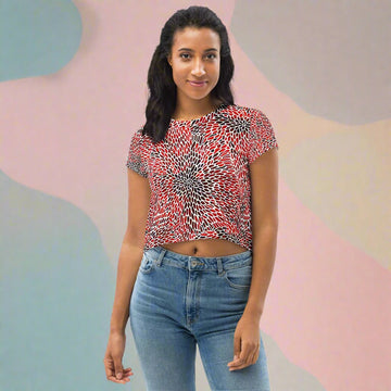 Vibrant abstract print crop tee in red, black, and white worn by a woman standing with blue jeans.