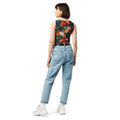 Model wearing a crop top with a winter rose floral design featuring vibrant red and cream roses on a deep green background, paired with light blue jeans.