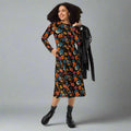 Model showcasing a vibrant black floral long sleeve midi dress with pockets.