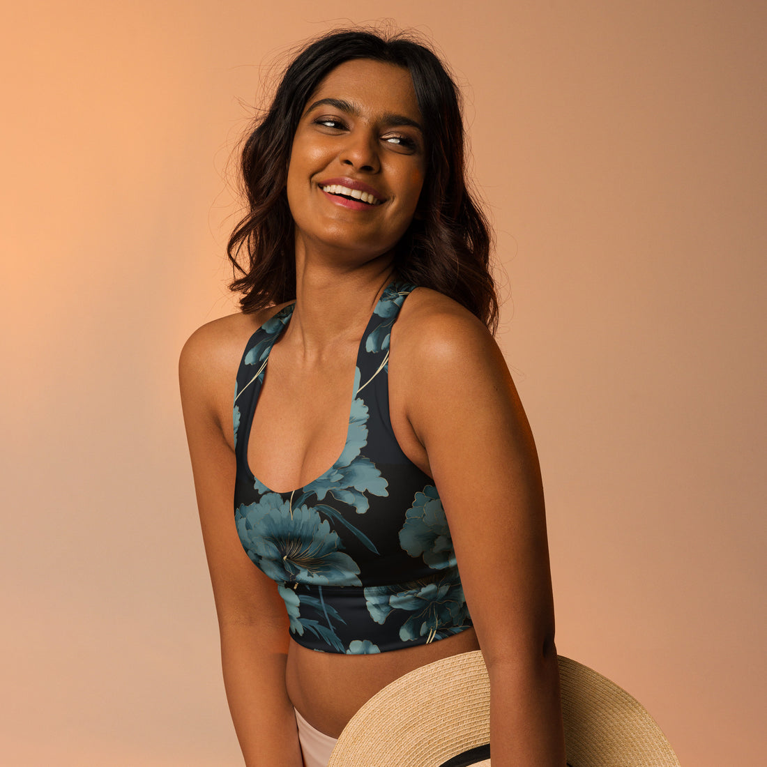 Floral Longline Sports Bra in black with teal floral print, model smiling with a straw hat against a soft peach background.