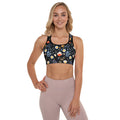 Woman wearing floral midnight sports bra with colorful floral print on black background, showcasing scoop neckline and racerback design