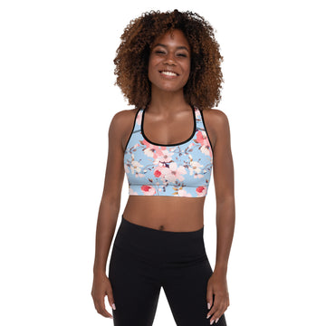 Woman wearing a cherry blossom patterned sports bra in soft pastel colors with black trim, ideal for workouts.