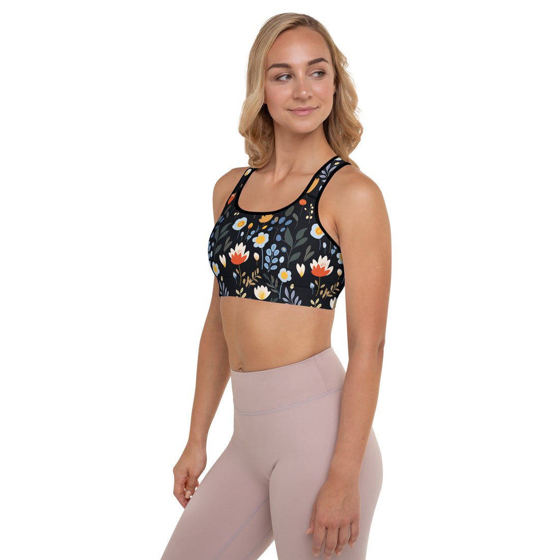 Woman wearing floral midnight sports bra with colorful floral print on black background, showcasing scoop neckline and racerback design