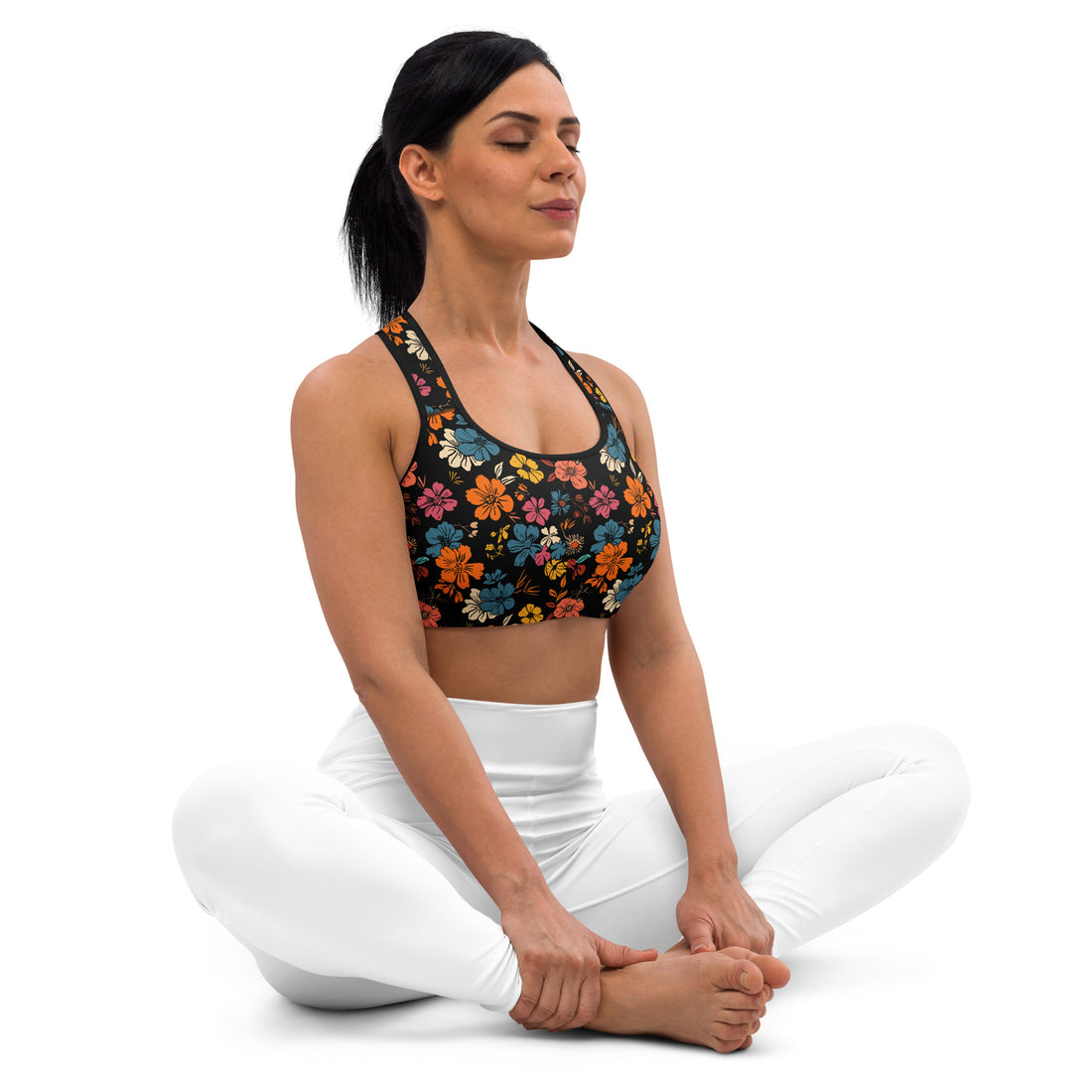 Woman wearing a Black Floral Mist Padded Sports Bra with vibrant orange, pink, and blue floral designs, demonstrating a yoga pose. The bra features a scoop neckline and racerback design.