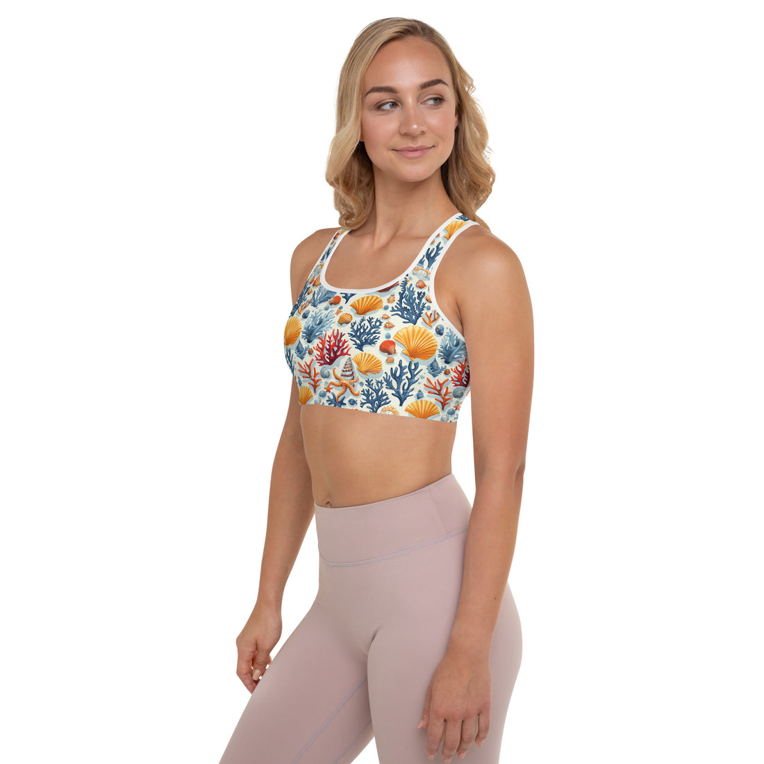 Woman wearing a padded sports bra with a vibrant coral reef design featuring orange and blue sea motifs.