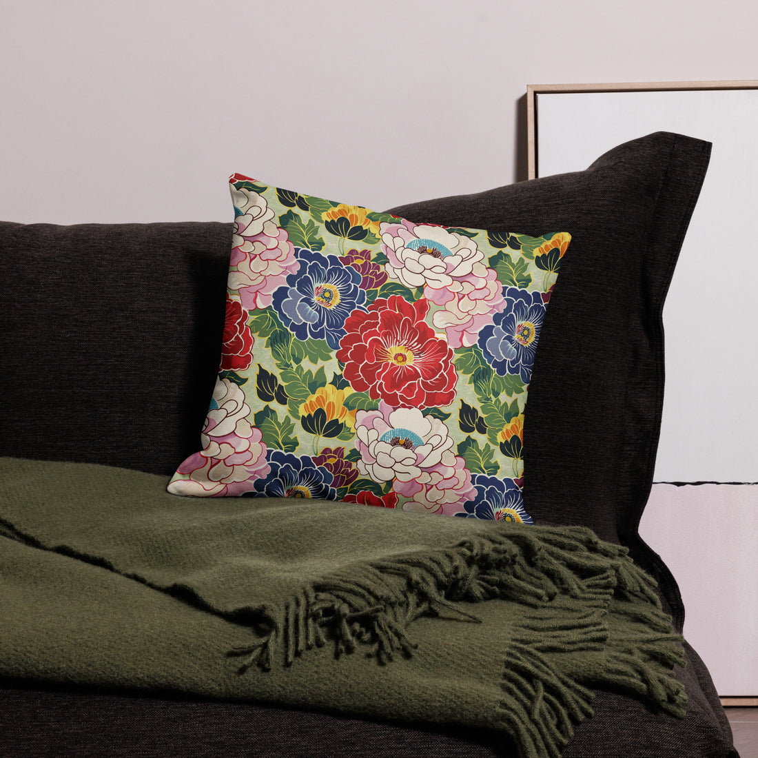 Cushion with vibrant peony floral design in red, pink, and blue, on a dark couch.