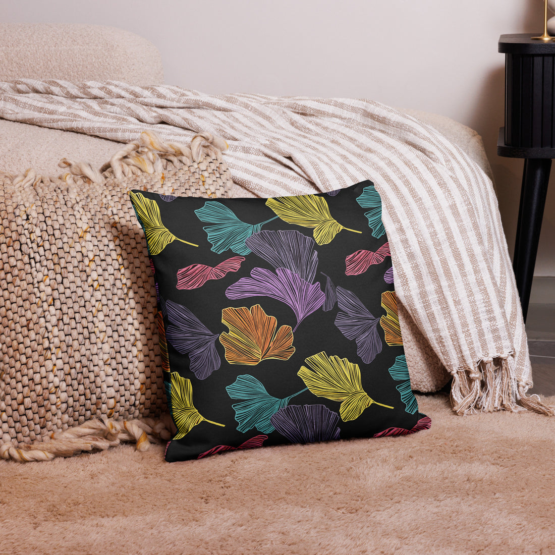 Cushion with multicolored Ginkgo leaf pattern on a luxurious fabric, featuring vibrant purple, green, yellow, and pink leaves against a dark background.