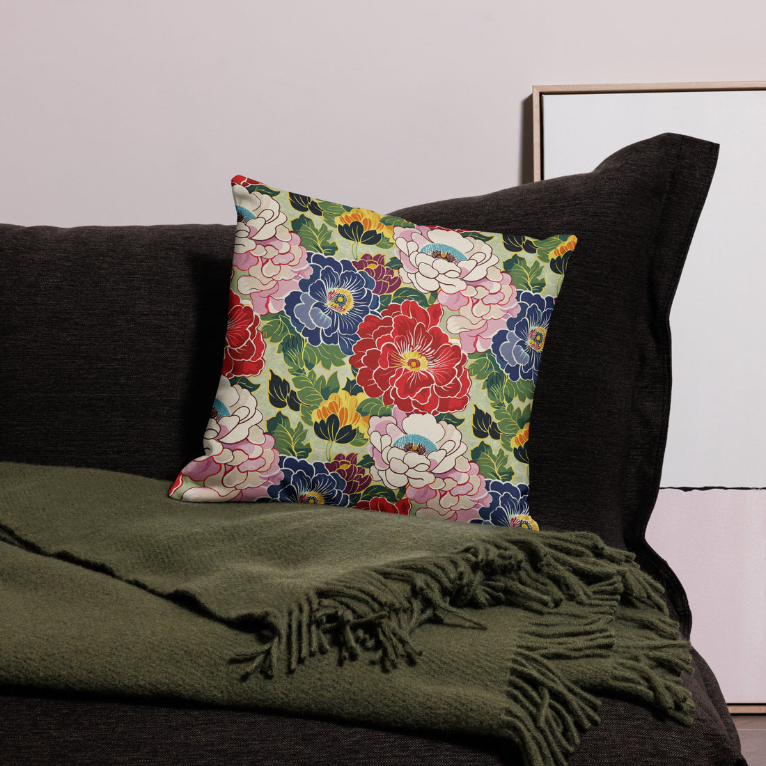 Cushion with vibrant peony floral design in red, pink, and blue, on a dark couch.