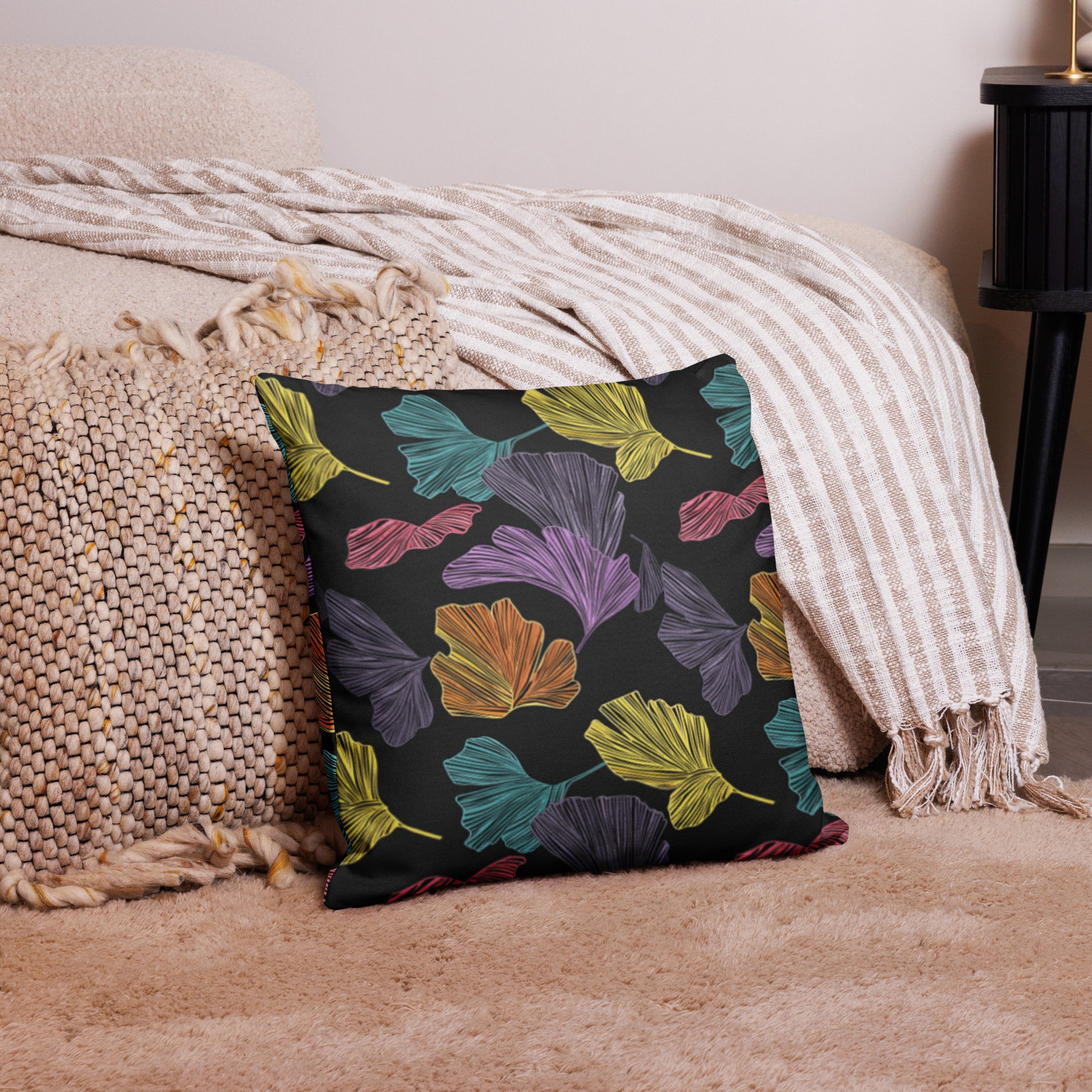 Cushion with multicolored Ginkgo leaf pattern on a luxurious fabric, featuring vibrant purple, green, yellow, and pink leaves against a dark background.