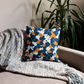 Knitted navy and orange pillow with houndstooth design on a couch, suitable for winter decor.