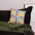 Pillow with vibrant abstract figures in red, blue, green, and yellow on a white background, adding a playful and colorful touch to home decor.