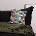 Colorful geometric patchwork pillow with vibrant blue, pink, and yellow knit patterns on a dark couch