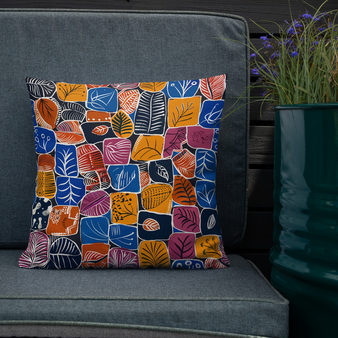 Accent pillow with colorful abstract leaf designs in blue, orange, and red hues against a deep background, perfect for seasonal home decor.