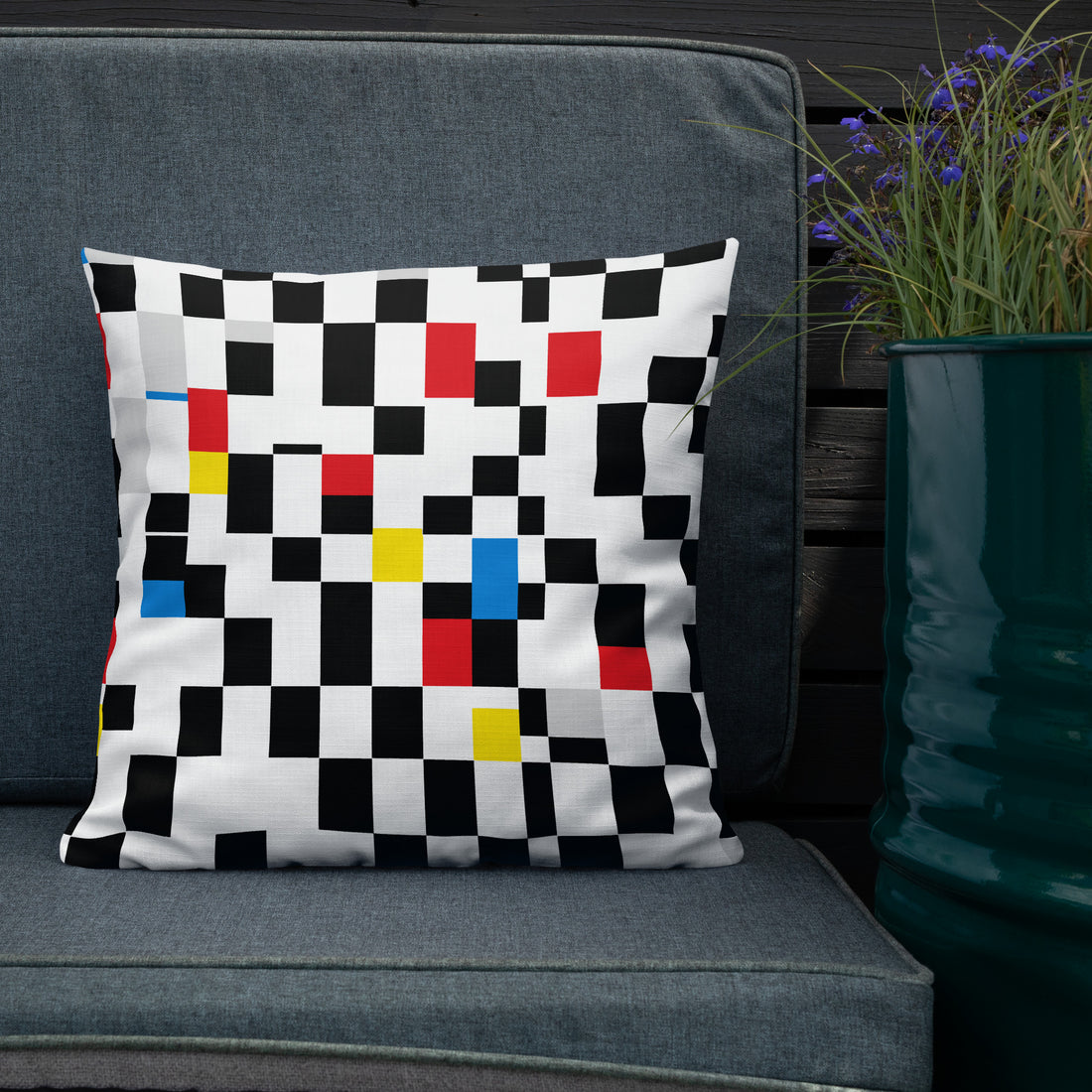 A cushion with a Mondrian-inspired design featuring vibrant geometric blocks in black, red, yellow, and blue, bringing a modern and festive touch to any room.