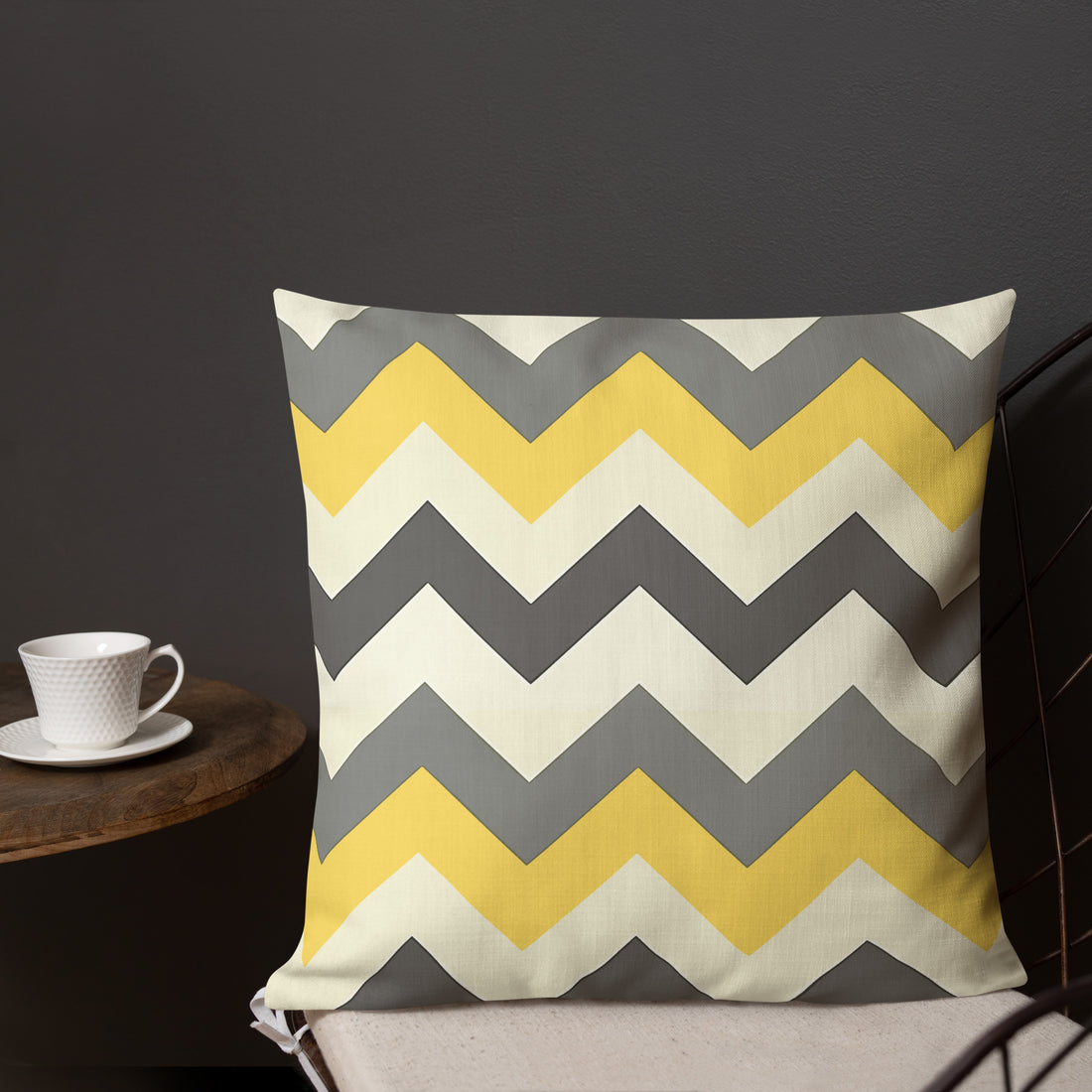 Chevron pattern premium pillow in yellow and gray on a sofa with coffee cup.