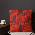 Red pillow with vibrant hibiscus floral pattern on a maroon background