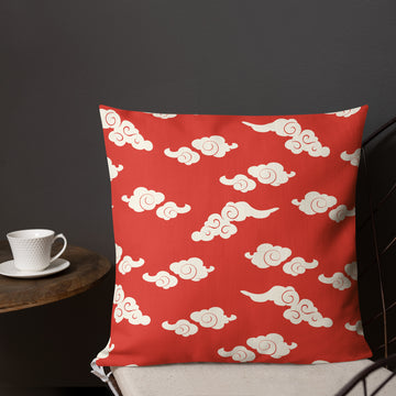 Red knitted pillow with cream-colored cloud patterns, perfect for festive home decor.