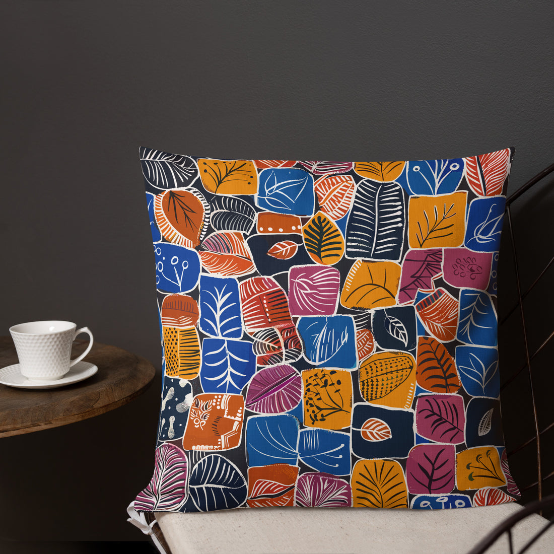 Accent pillow with colorful abstract leaf designs in blue, orange, and red hues against a deep background, perfect for seasonal home decor.