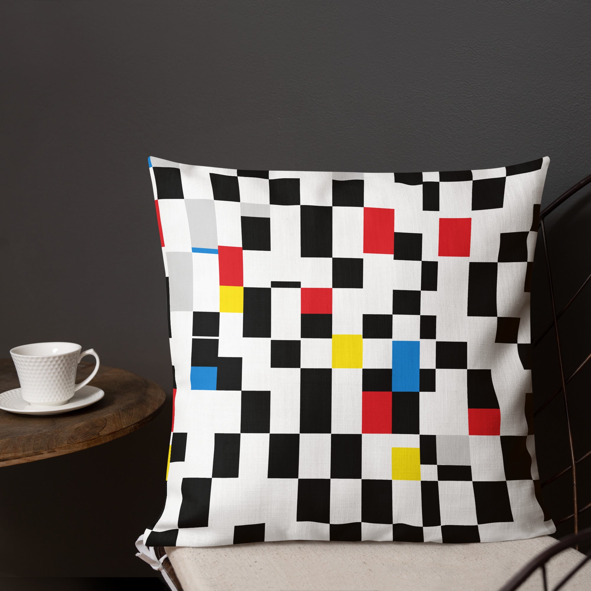 A cushion with a Mondrian-inspired design featuring vibrant geometric blocks in black, red, yellow, and blue, bringing a modern and festive touch to any room.