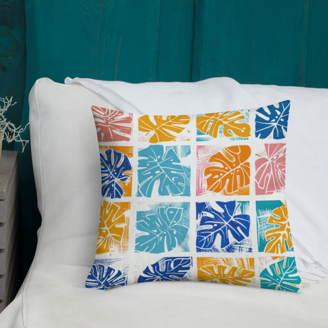 Premium pillow with colorful monstera leaf design in teal, coral, blue, and yellow. Knitted, not printed.