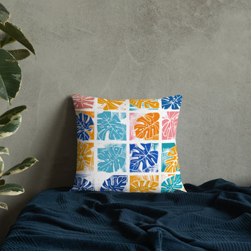 Premium pillow with colorful monstera leaf design in teal, coral, blue, and yellow. Knitted, not printed.