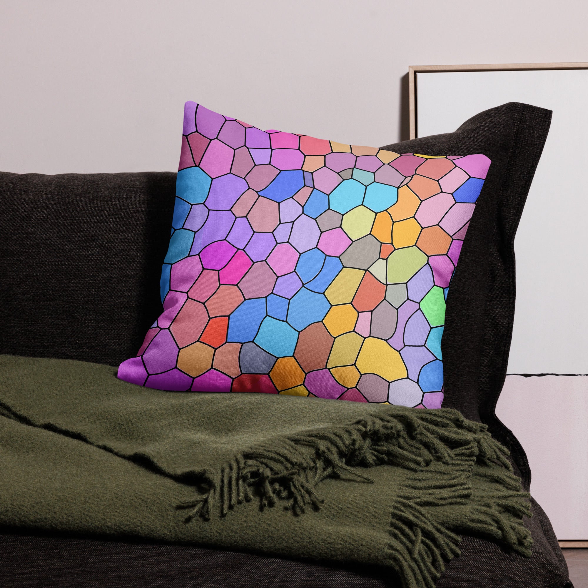 Colorful geometric premium pillow with a vibrant hexagonal pattern in shades of pink, blue, and yellow, displayed on a dark couch with a green throw blanket.