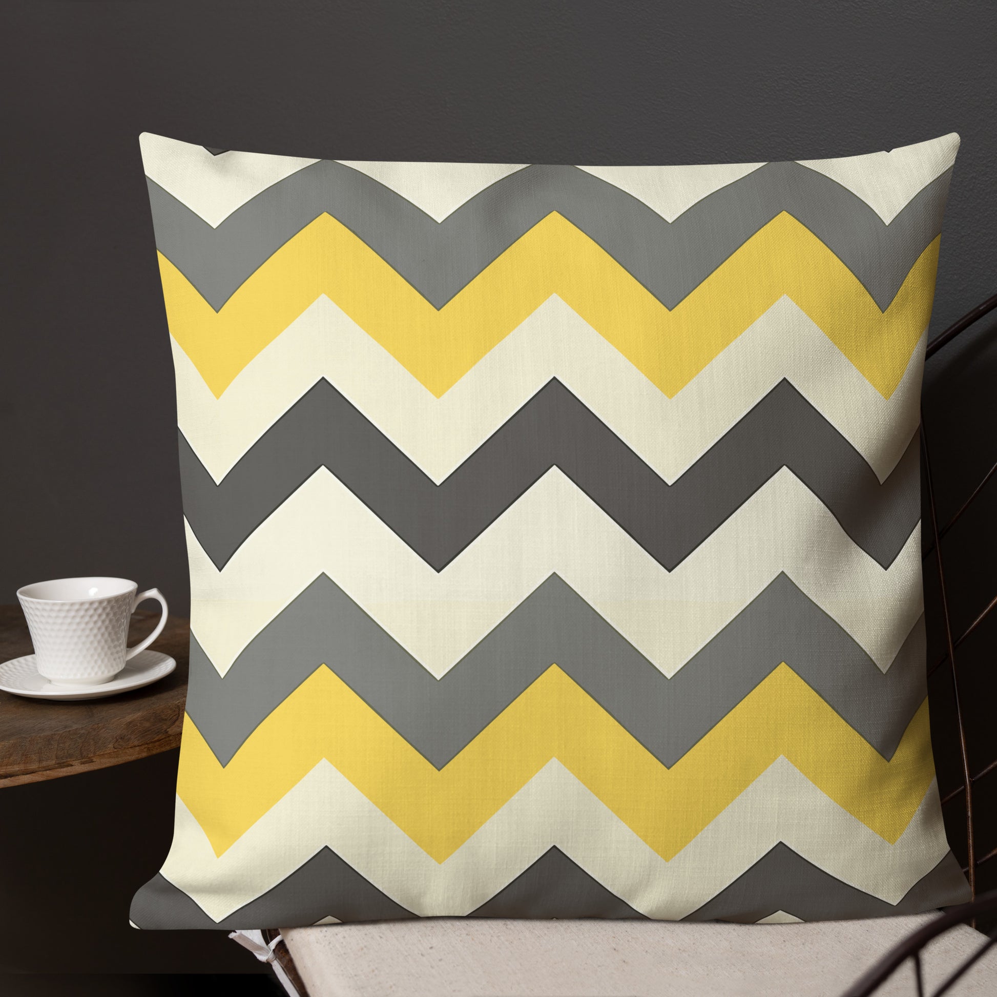 Chevron pattern premium pillow in yellow and gray on a sofa with coffee cup.