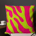 Vibrant abstract wave pattern pillow in pink and lime green colors on a chair with a cup nearby.