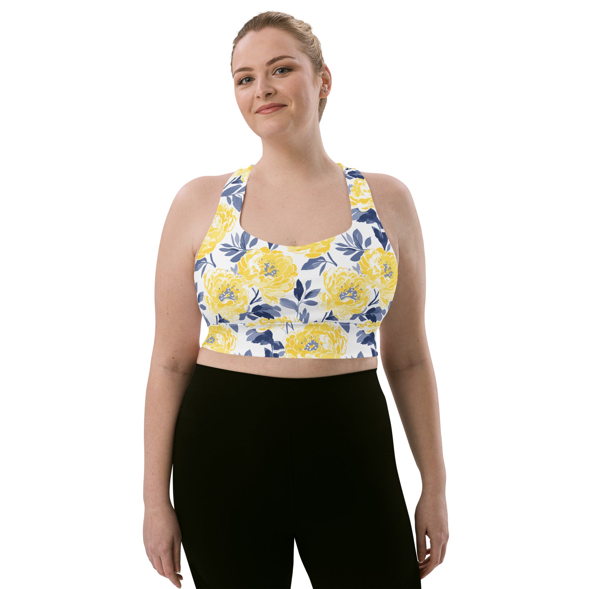 Woman wearing a longline sports bra with a bright yellow floral design on a white background, providing a vibrant and stylish look.