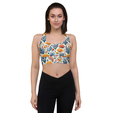 Woman wearing a colorful sports bra featuring a coral and seashell pattern in shades of orange, blue, and teal.