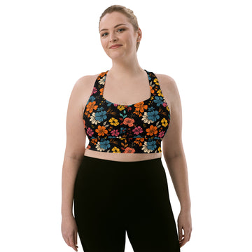 Model wearing a longline sports bra with a vibrant floral pattern, featuring colorful flowers on a black background.