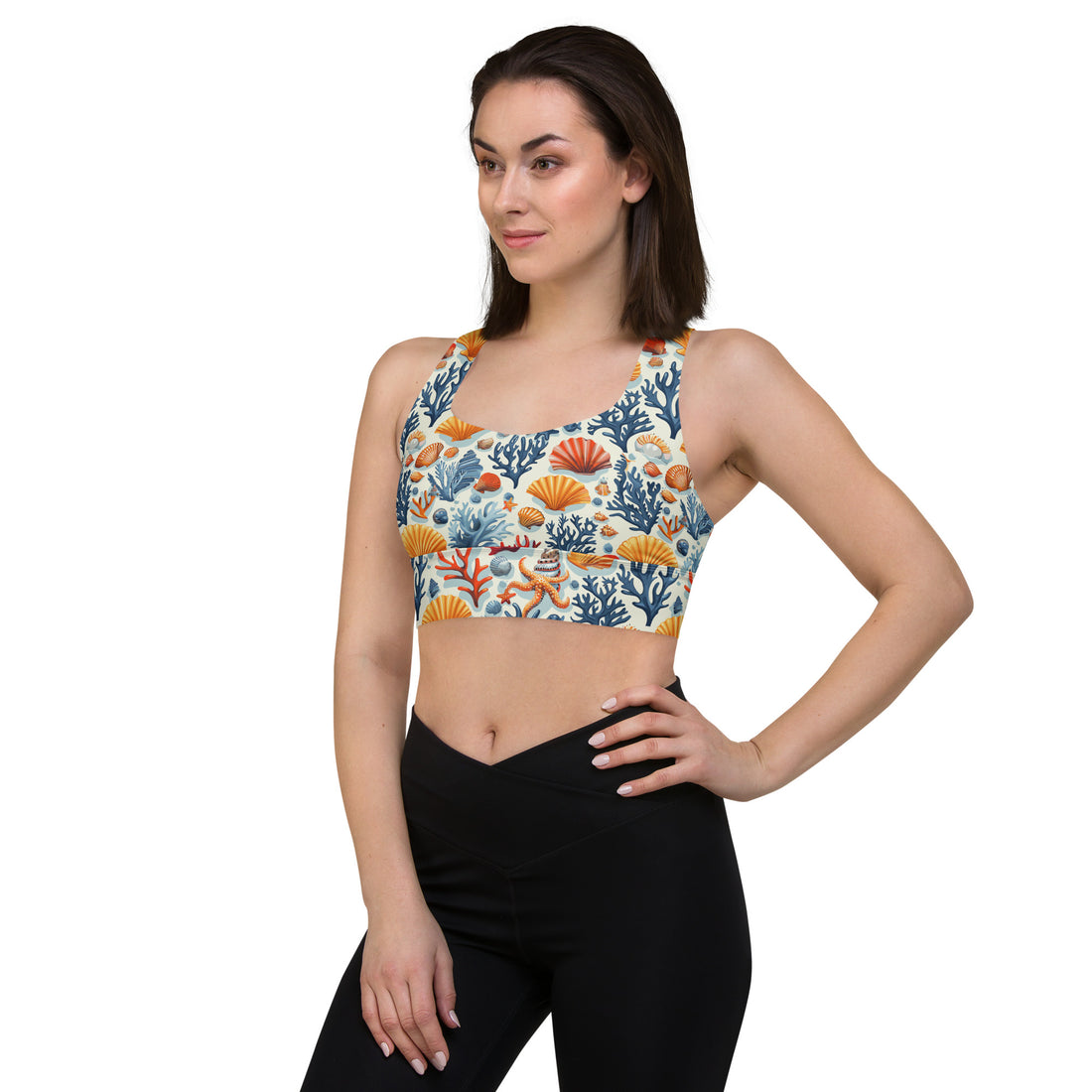 Woman wearing a colorful sports bra featuring a coral and seashell pattern in shades of orange, blue, and teal.