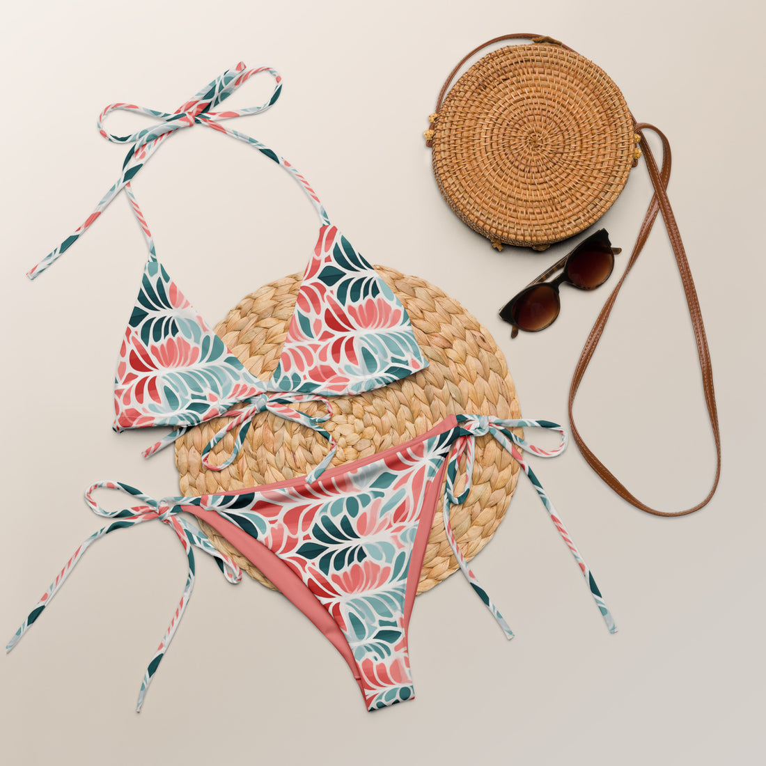 Model wearing a floral print recycled string bikini in coral and teal colors.