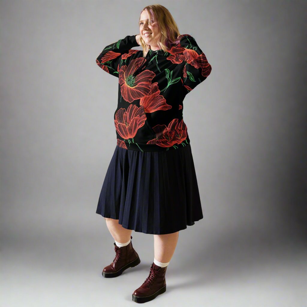 A woman wearing a floral vintage print unisex hoodie with red flowers on a black background, paired with a navy pleated skirt.