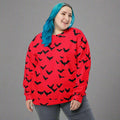 A vibrant red sweatshirt featuring an all-over bat print design, perfect for Halloween.