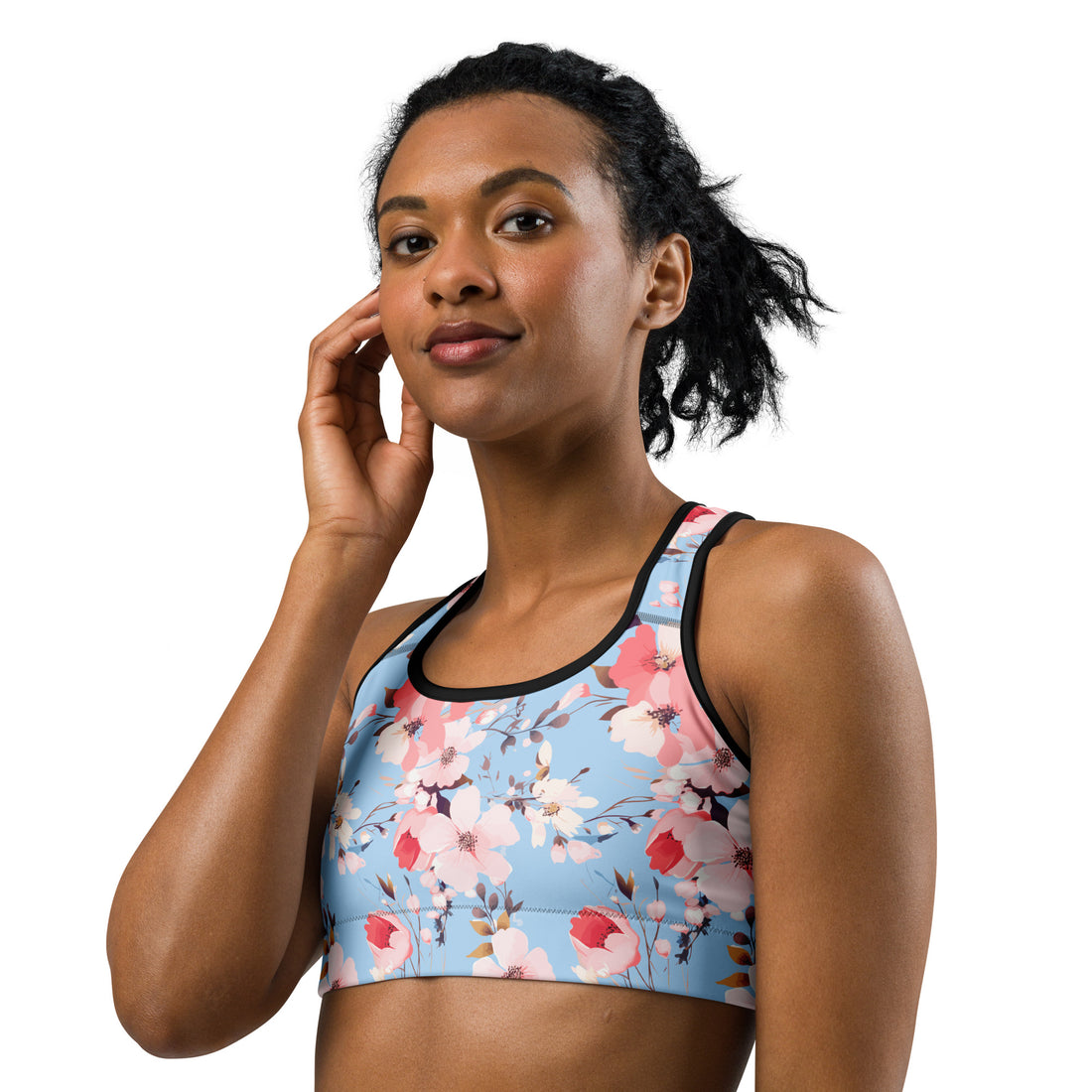 Woman wearing a floral sports bra with pink and coral blossoms on an icy blue background, suitable for winter holiday workouts.