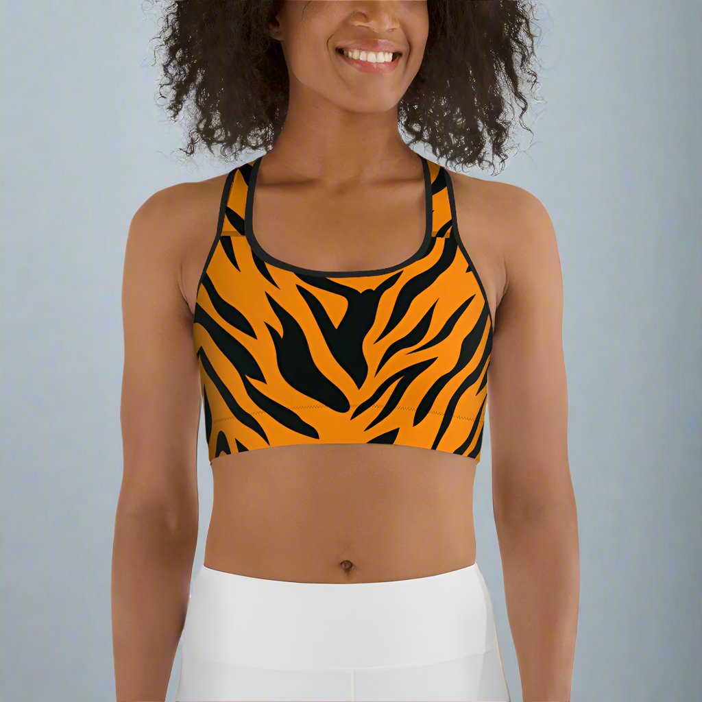 Orange and black tiger print sports bra on a smiling woman with curly hair.