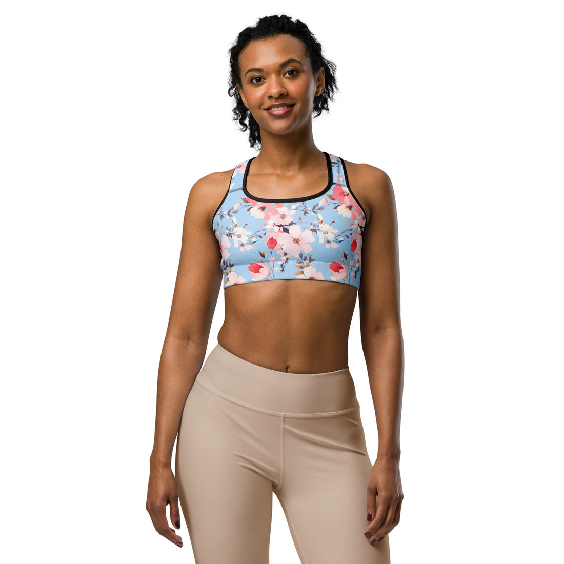 Woman wearing a floral sports bra with pink and coral blossoms on an icy blue background, suitable for winter holiday workouts.